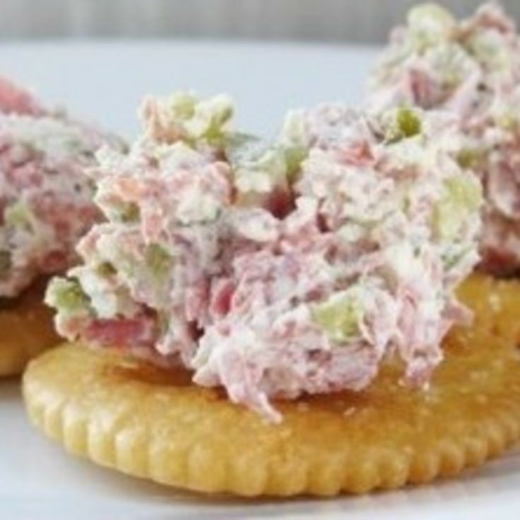 three crackers topped with crab salad on top of a white plate