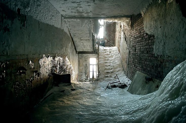 an alley way with snow on the ground and light coming in from two windows at one end