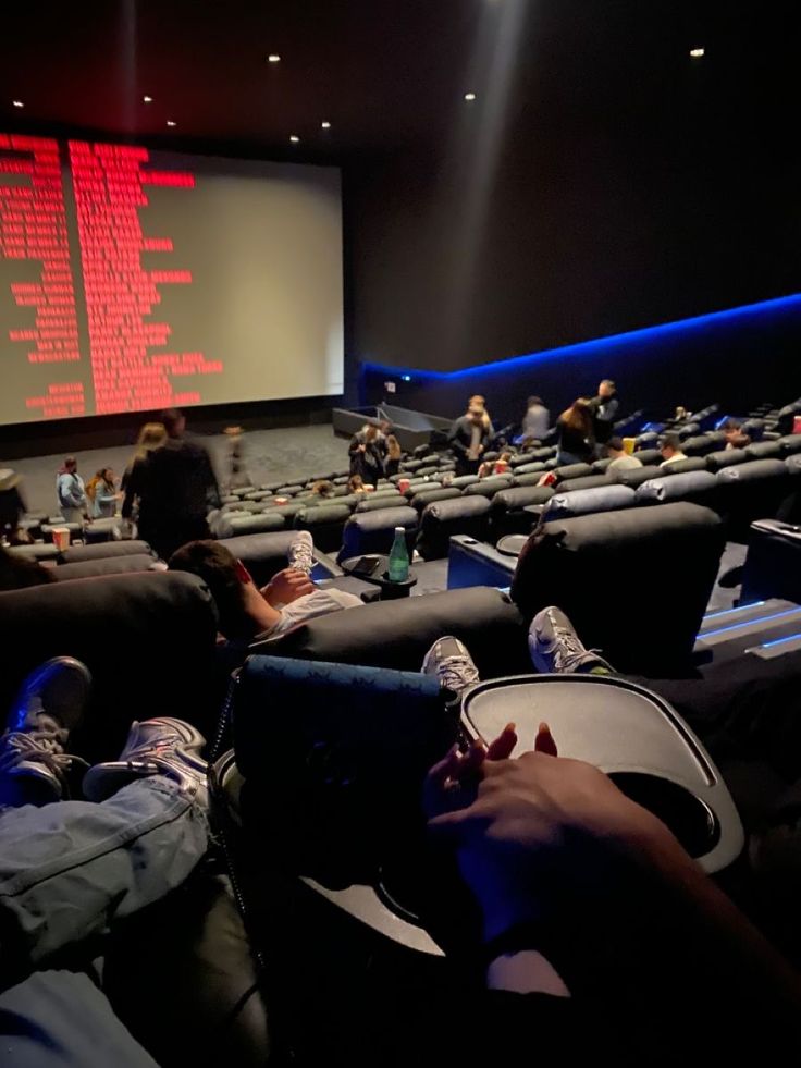 people are sitting in chairs watching movies on the big screen at the movie theater or auditorium