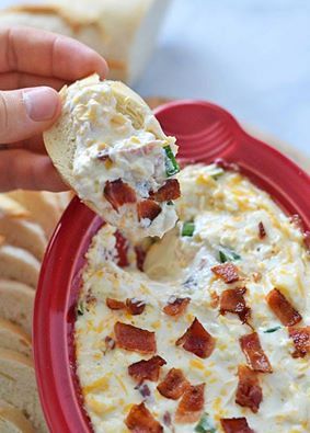 a person dipping some food into a red bowl with crackers on the side to eat it