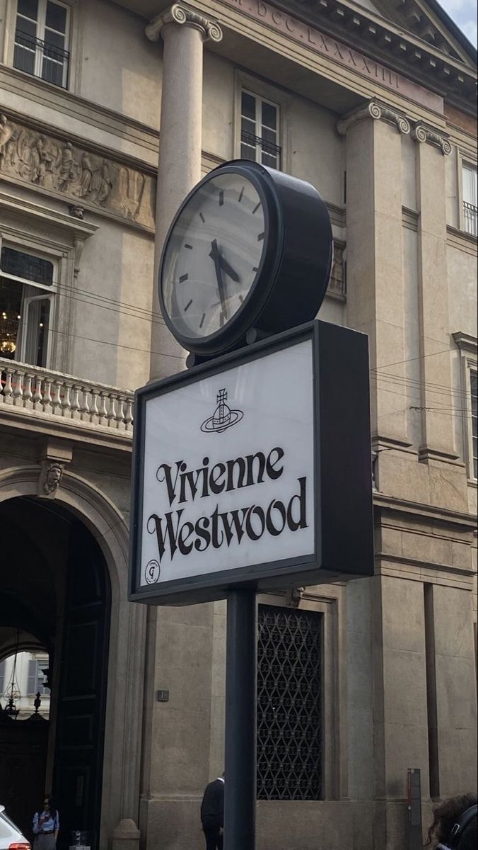 a clock on top of a sign in front of a building