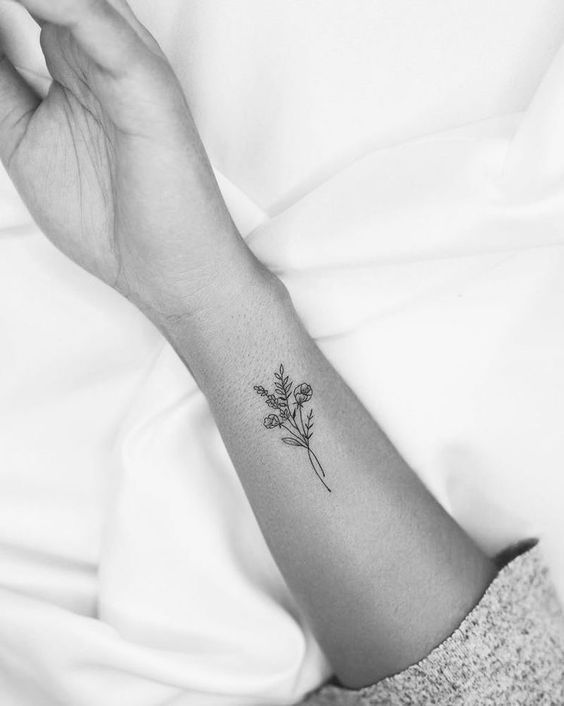 a woman's arm with a small flower tattoo on the left side of her wrist