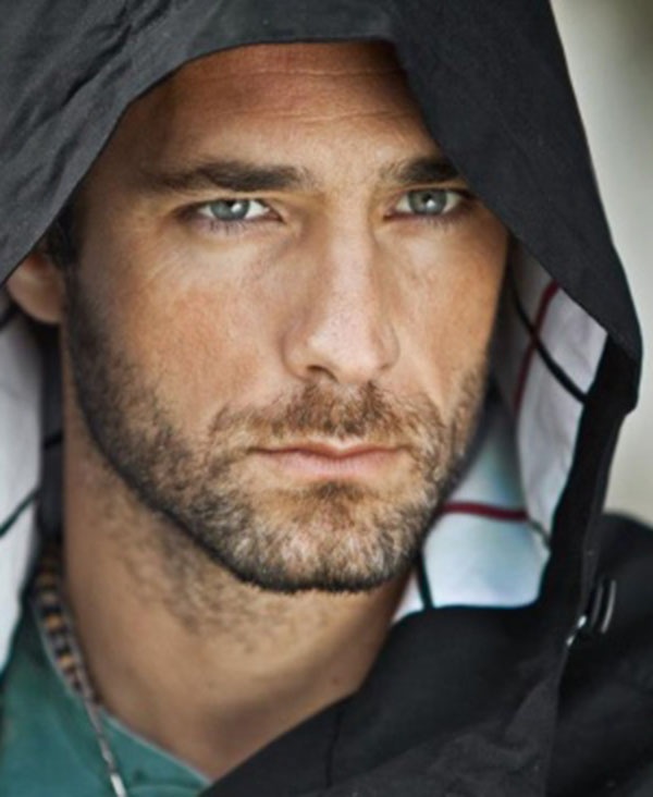 a man wearing a hoodie looking at the camera with a serious look on his face