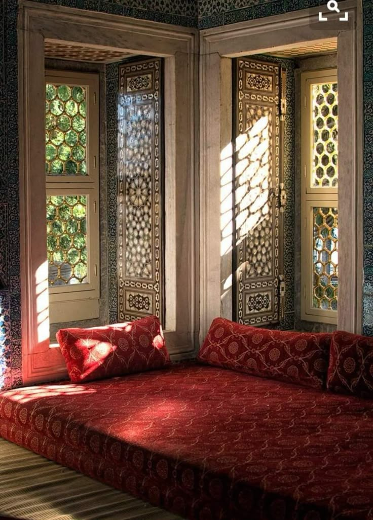 a red couch sitting in front of two windows