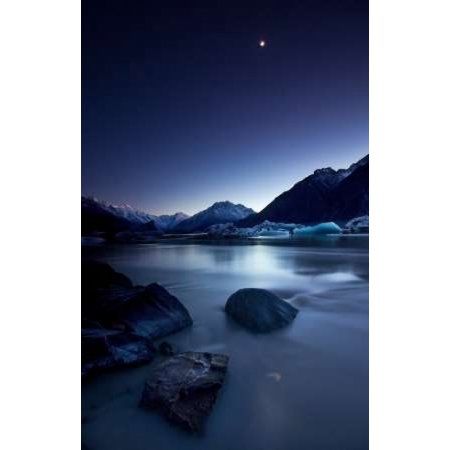 the moon is setting over some mountains and water with icebergs in the distance