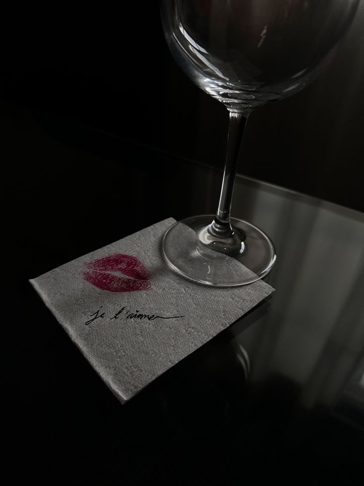 a wine glass sitting on top of a table next to a napkin with a lipstick imprint