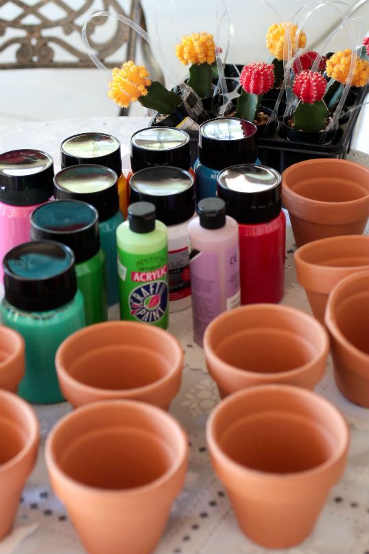 there are many pots and cups on the table with some flowers in the vases