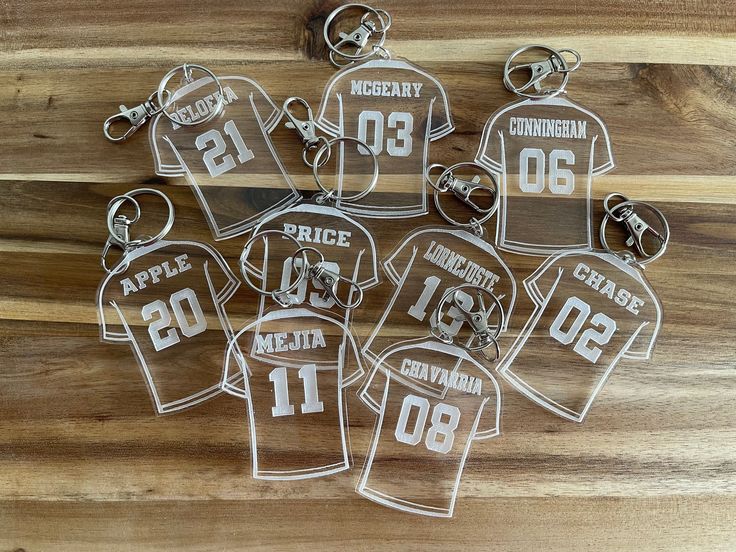 six keychains that have been cut out to look like football jerseys with numbers on them