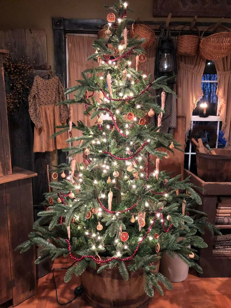 a small christmas tree in a pot with lights on it's branches and decorations