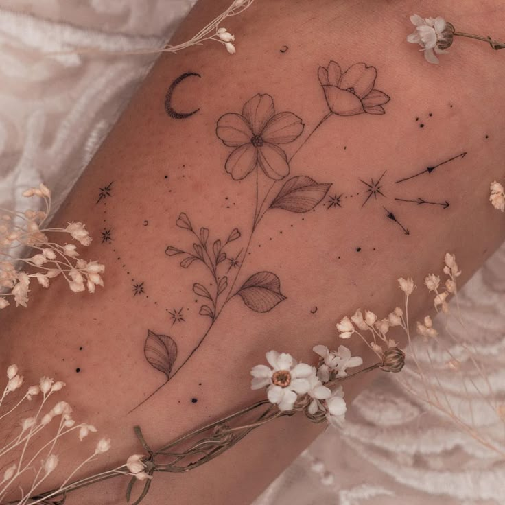 a close up of a person's arm with flowers and stars on the side