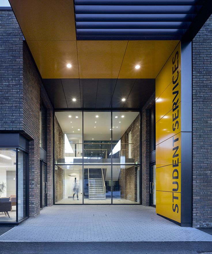 the entrance to an office building that has glass doors and yellow signage on it's side