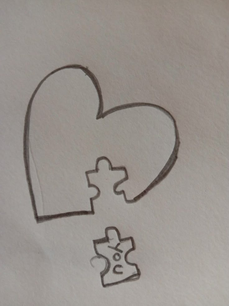 a piece of paper with a heart and two pieces of a puzzle on top of it