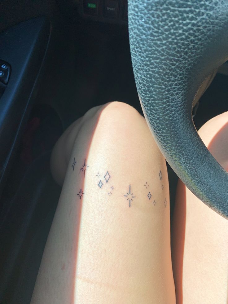 a person with tattoos on their legs sitting in a car next to a steering wheel