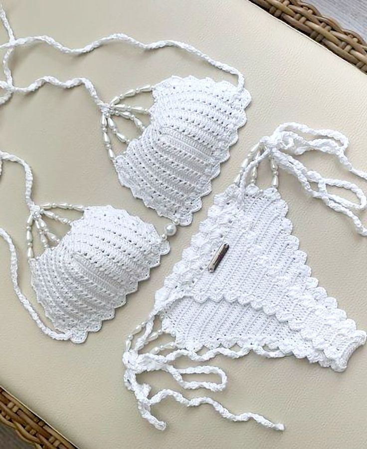 two crocheted pieces of white material on a table