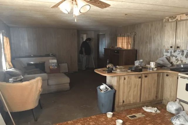 a man standing in a kitchen next to a stove top oven under a ceiling fan