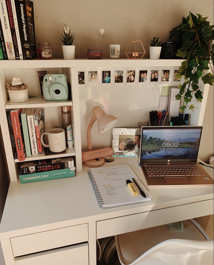 a laptop computer sitting on top of a white desk next to a book shelf filled with books