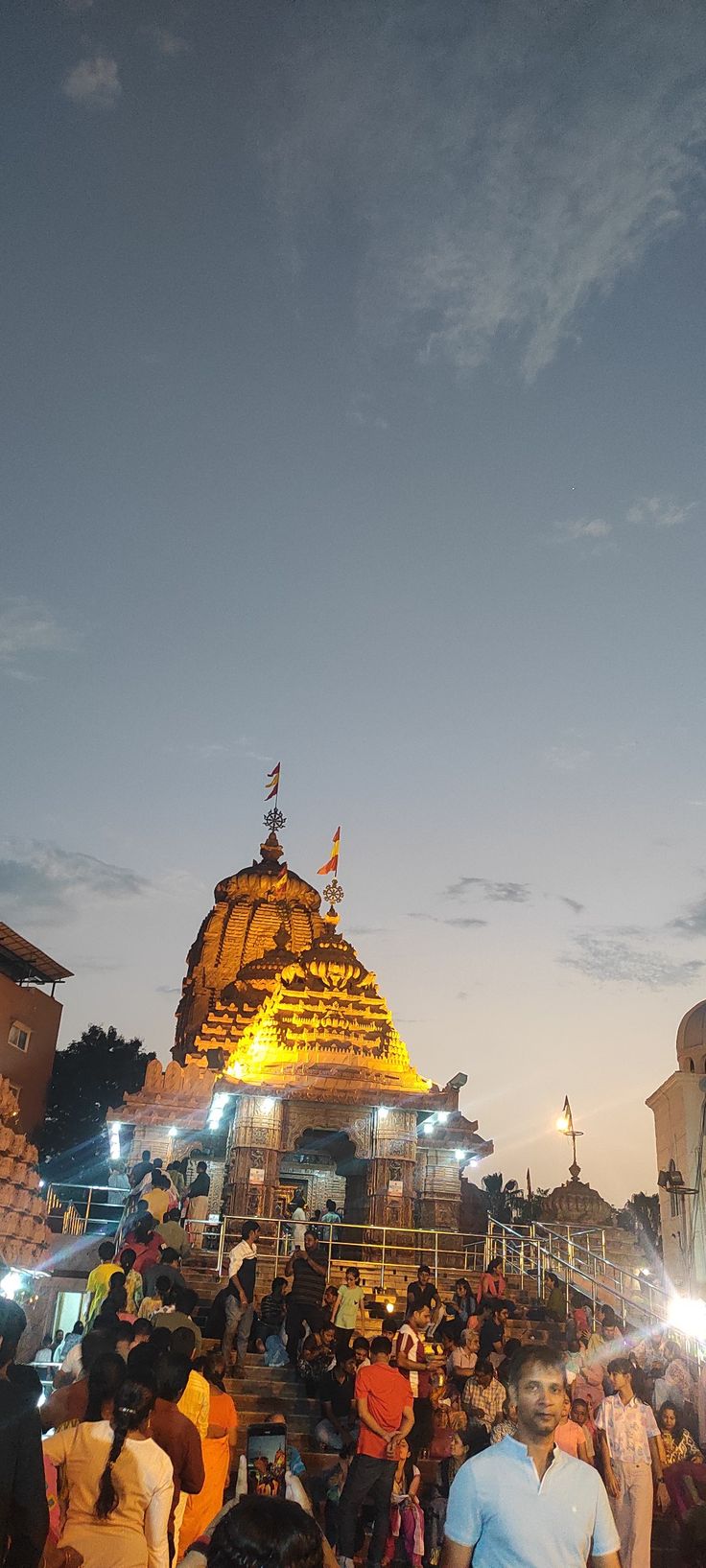 many people are standing around in front of a large building at night with bright lights