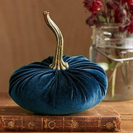 a blue velvet pumpkin sitting on top of a book