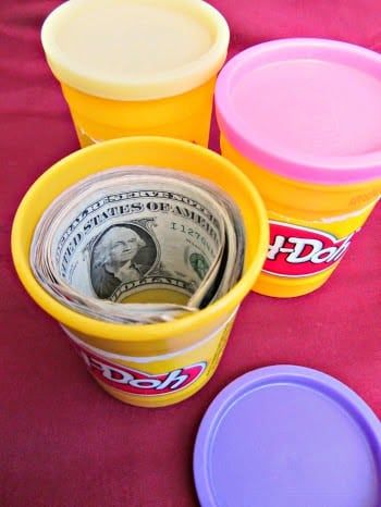 three plastic cups filled with money sitting on top of a red cloth covered tablecloth