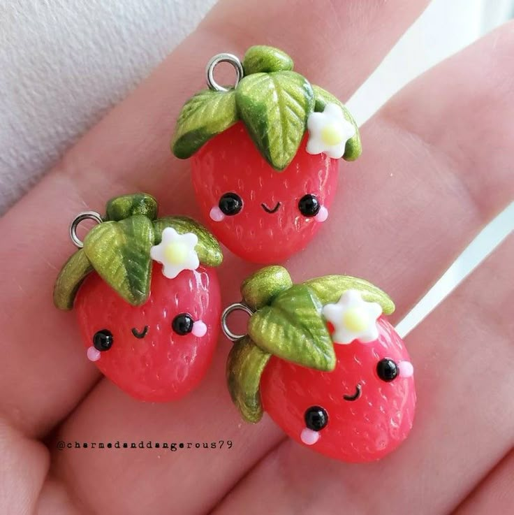 two little strawberrys are sitting on someone's hand, one is wearing a flower and the other has a green leaf