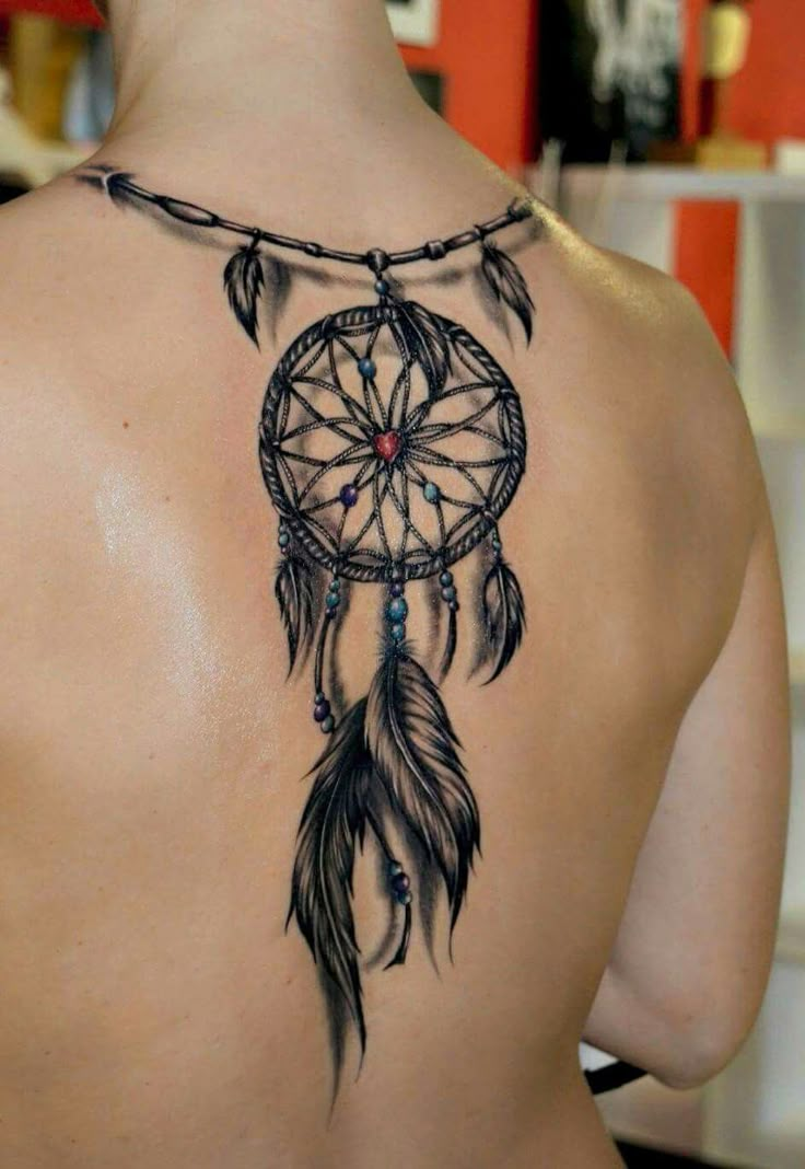 the back of a woman's shoulder with a dream catcher tattoo on her upper