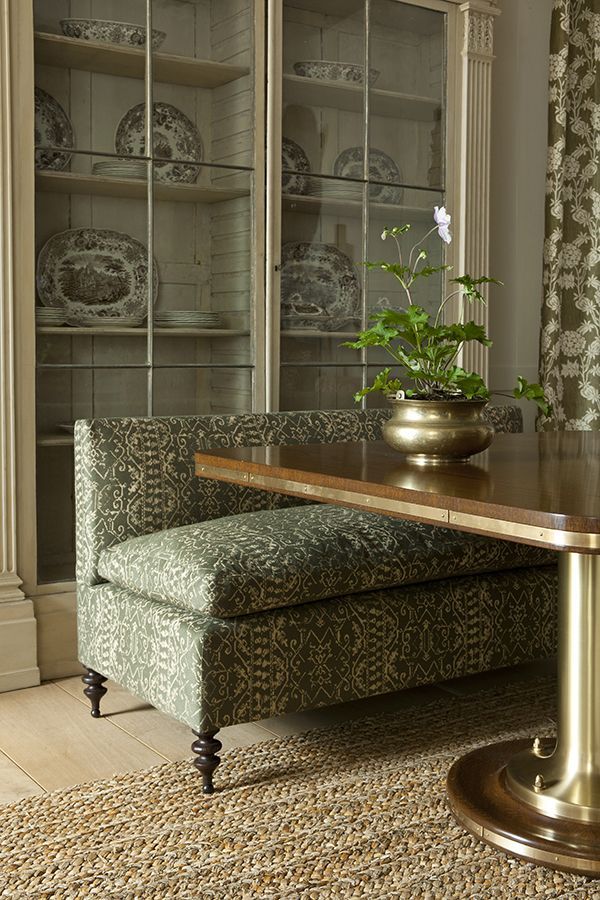 a living room with a bench and vase on the table in front of glass doors