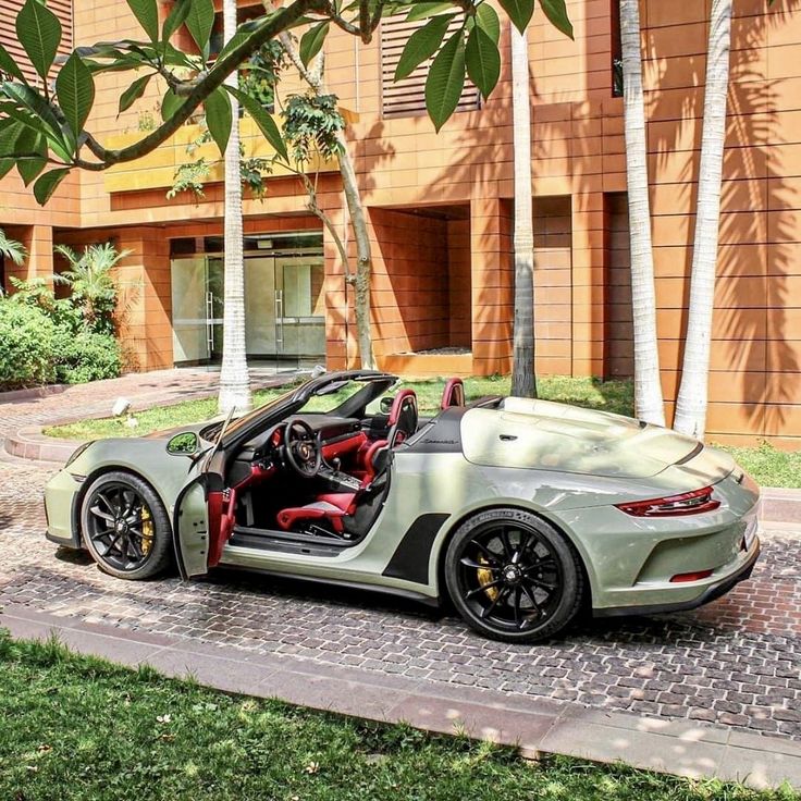 a green sports car parked in front of a building with its doors open and the driver's seat down