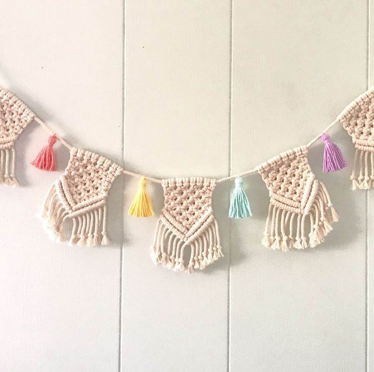 a crocheted string with tassels hanging from it on a white wall