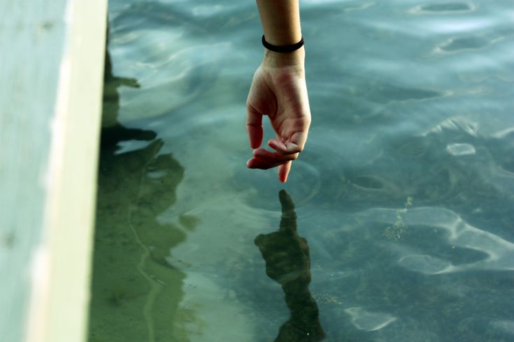 a person's hand reaching for something in the water