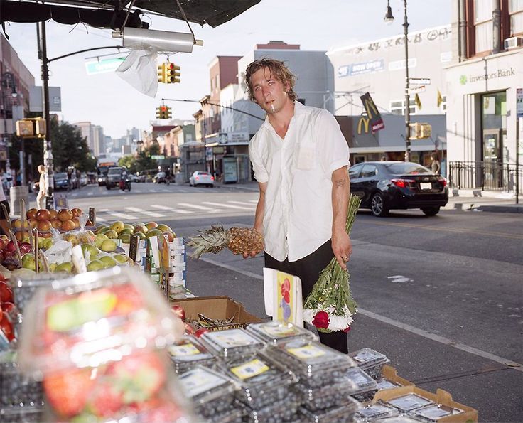 a man standing in front of a fruit stand