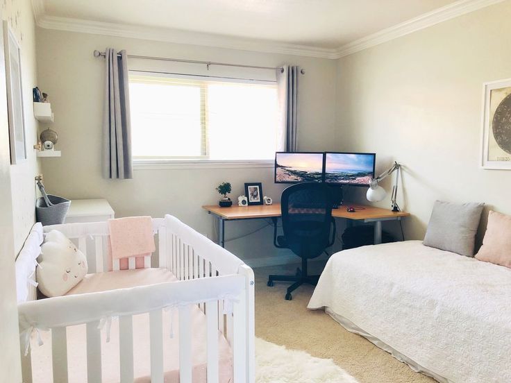 a baby's room with a bed, desk and computer monitor on the wall