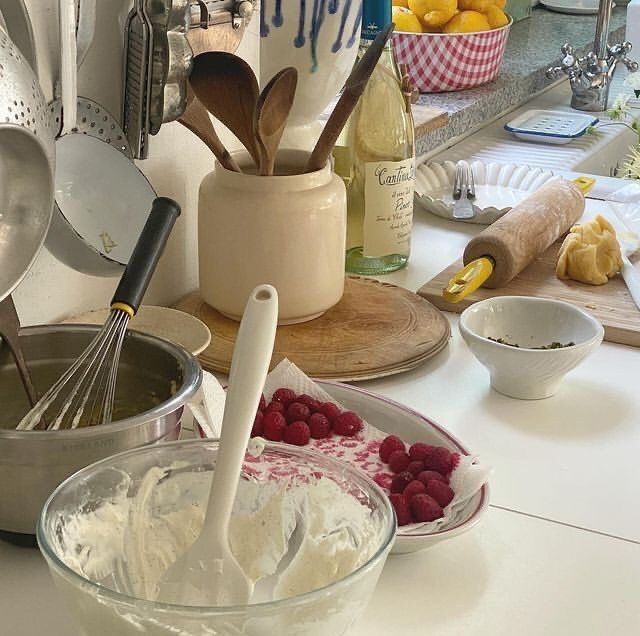 the kitchen counter is cluttered with dishes and utensils, including raspberries