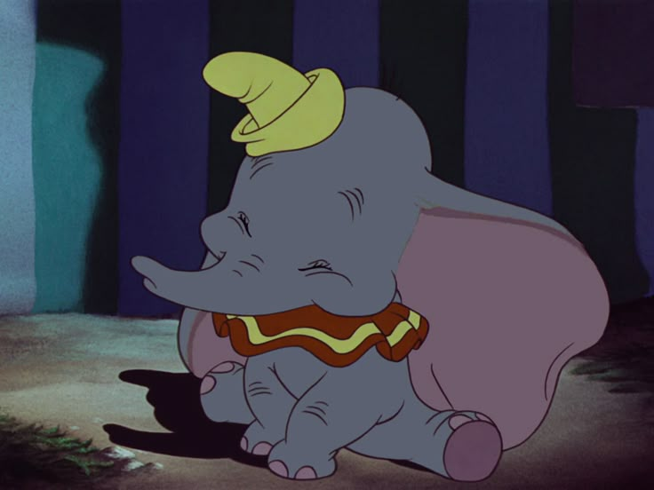 an elephant with a hat and scarf around its neck sitting on the ground in front of striped walls