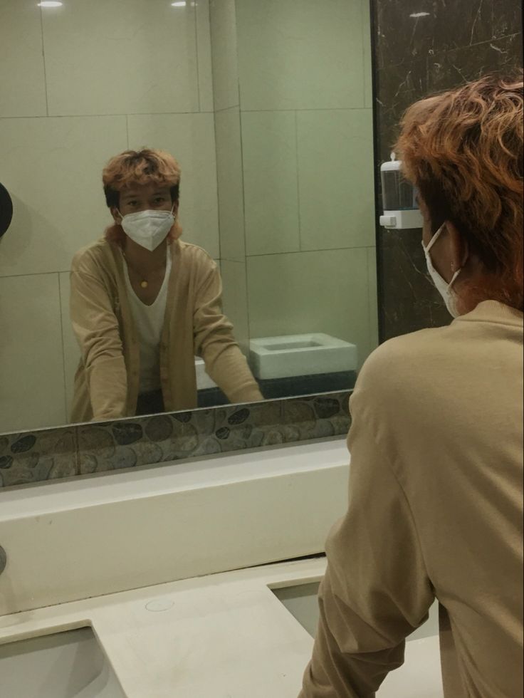 a man in a mask is looking at himself in the mirror