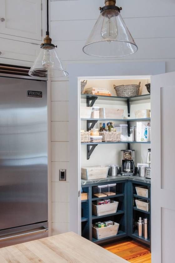 an open pantry with lots of items in it and hanging lights above the refrigerator door