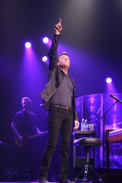 a man standing on top of a stage holding his hand up