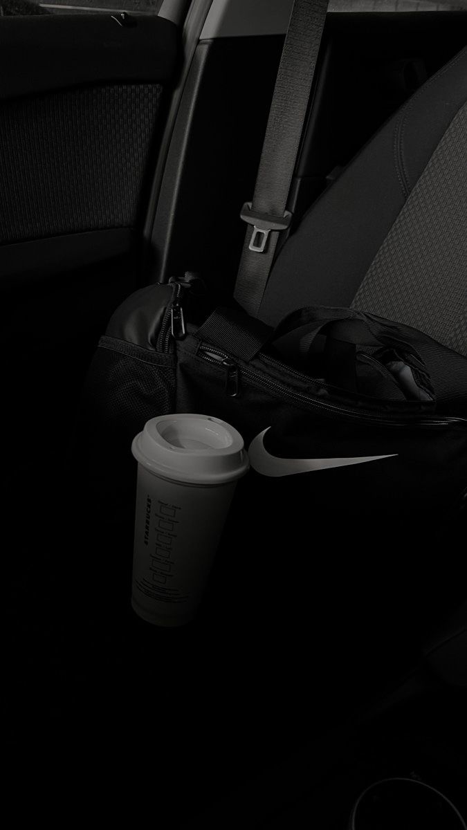 the back seat of a car with a cup and backpack on it's side