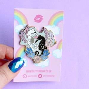 a hand holding a pin with a sea horse on it