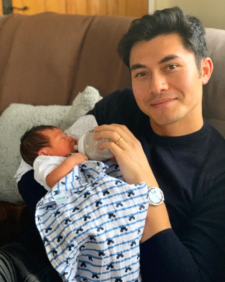 a man sitting on a couch holding a baby