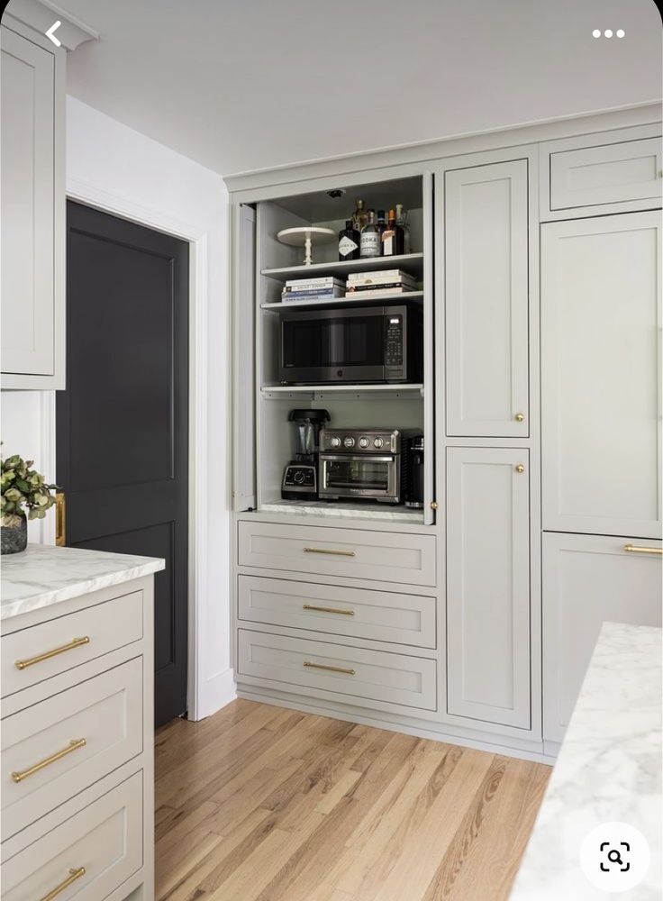 a kitchen with white cabinets and wood floors