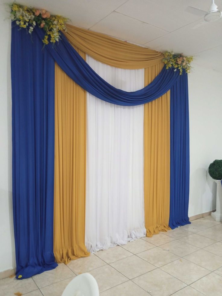 a white toilet sitting next to a blue and yellow drape on a tiled floor