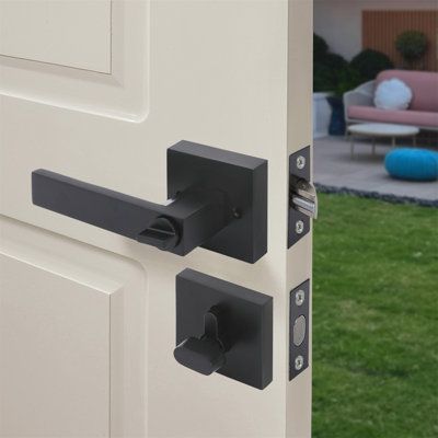 an open door with black handles and knobs on the outside of it, in front of a house