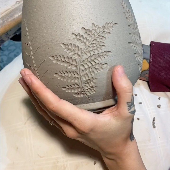 a person holding a vase in their hand with designs on the outside and inside of it