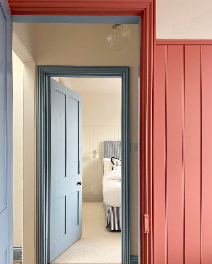 an open door leading to a bedroom with a bed in the background and red painted walls