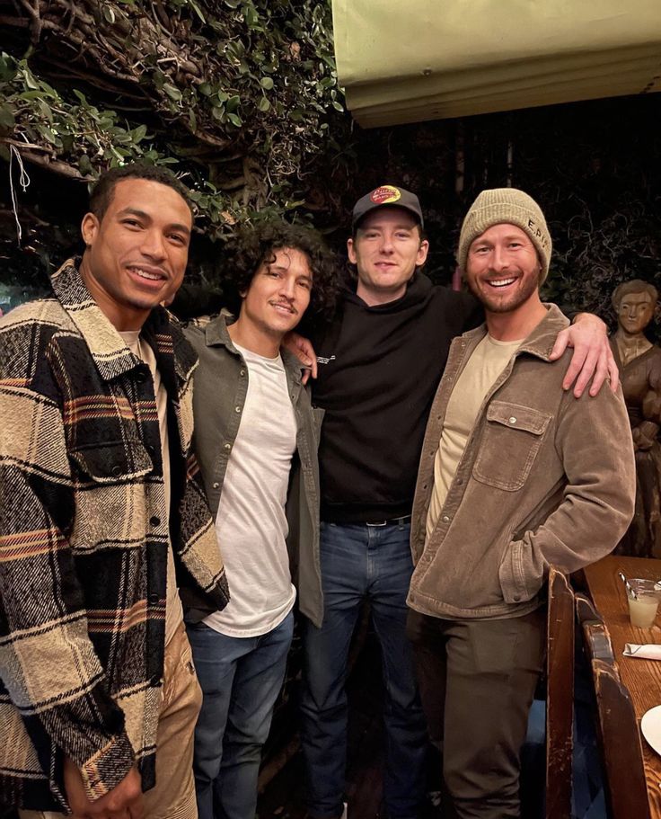 three men standing next to each other in front of a table with food on it