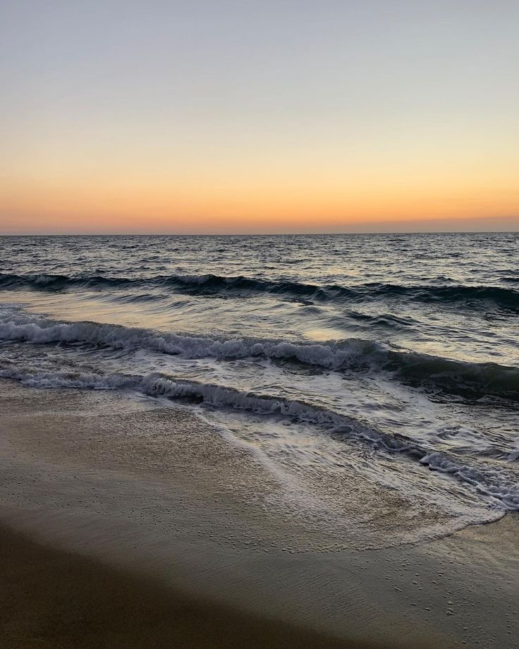 the sun is setting over the water at the beach