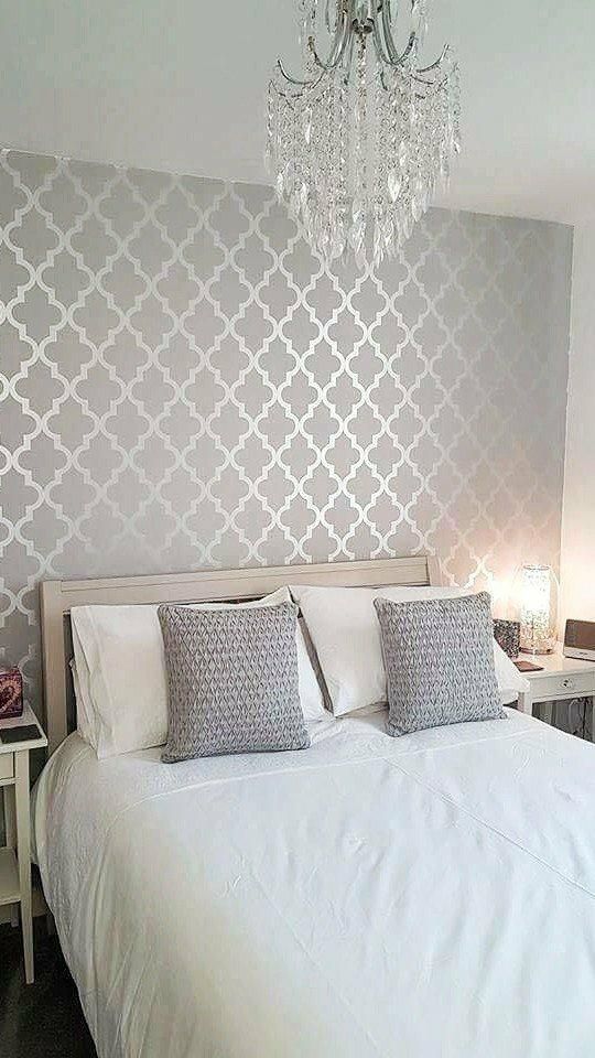 a white bed sitting under a chandelier in a bedroom