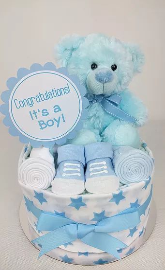 a blue teddy bear sitting on top of a baby boy gift basket filled with items