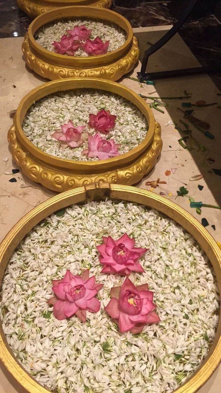 three gold frames with pink flowers in them on a table next to white and green rice