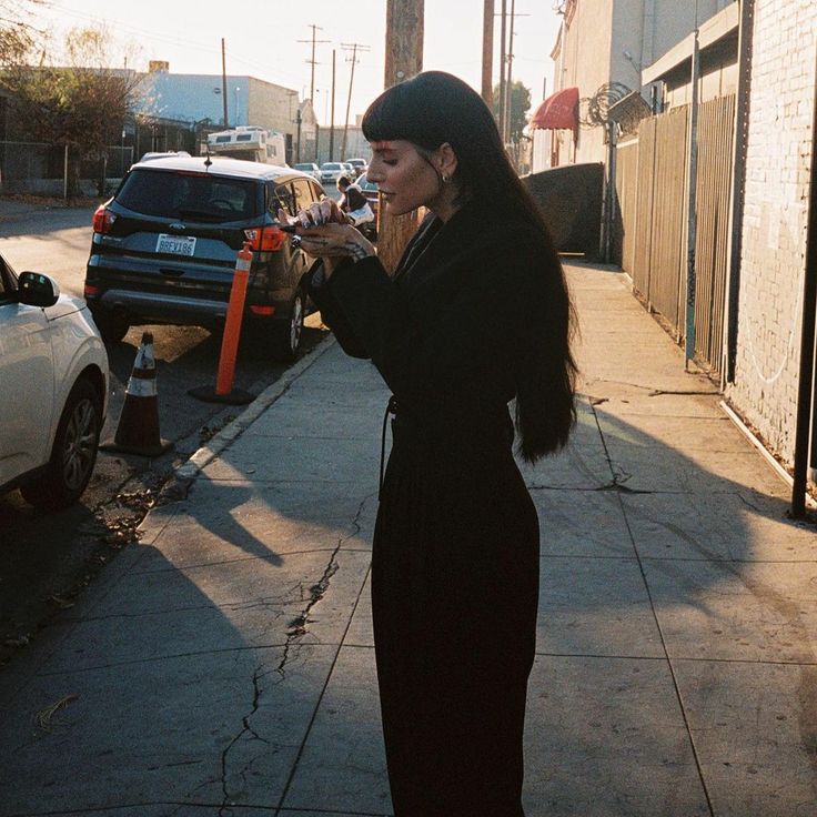 a woman standing on the sidewalk talking on her cell phone